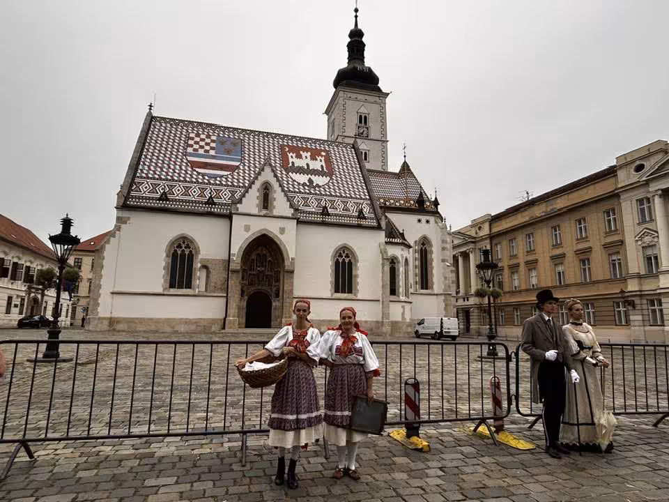 Croatian folk dancers in traditional costumes at St. Mark's Square Zagreb with colorful tiled church