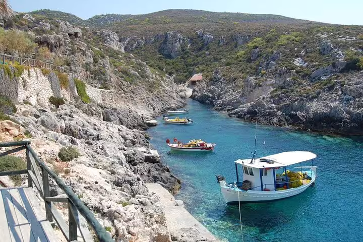 Small boats in a turquoise rocky cove, perfect stop on Southern Zakynthos half-day tour beaches and viewpoints