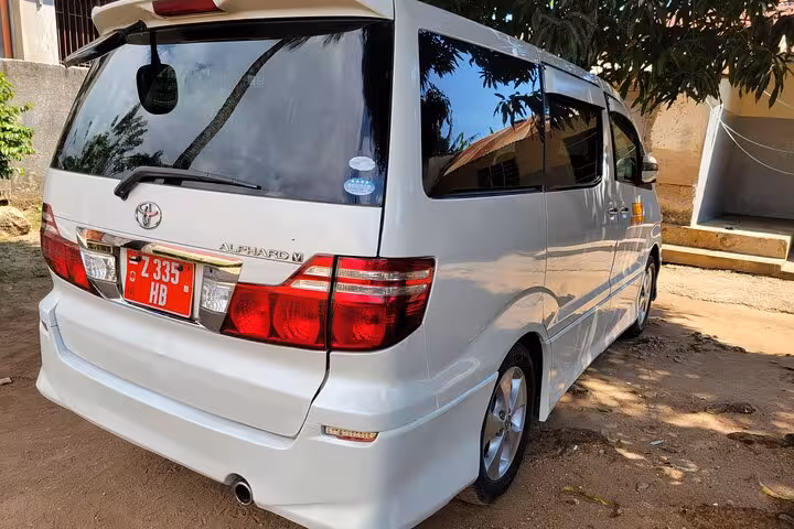 Rear view of white van for private airport transfer service to Nungwi hotels, Zanzibar, highlighting 24/7 availability.