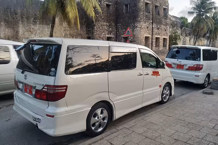 White shuttle vans parked in Zanzibar, ready for private round trip airport transfers, offering convenience and comfort.