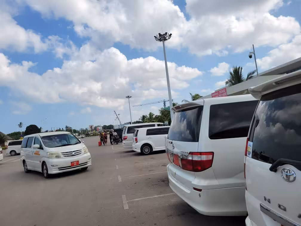 Fleet of airport taxis at Zanzibar airport, providing private transfer services to Pongwe hotels under a clear sky.