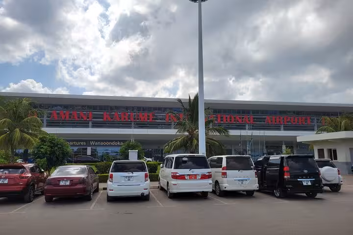 Parking area outside Abeid Amani Karume International Airport with various vehicles.