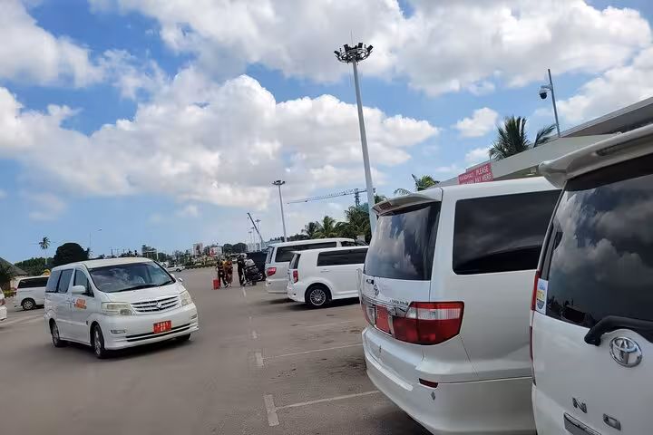 Private transfer vehicles at Zanzibar airport parking, ready for East Coast hotel transport service.