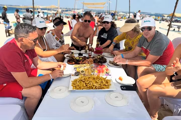 Group enjoying a vibrant seafood feast on a sunlit Zanzibar beach, showcasing culinary delights and island adventure.