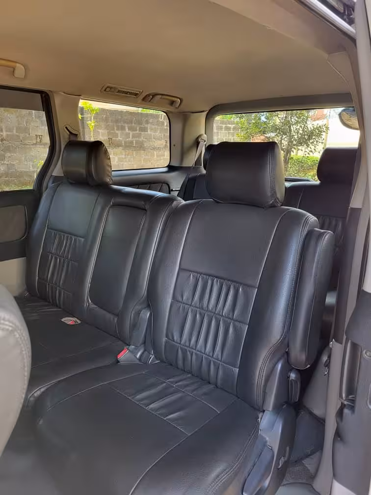 Spacious interior of a private airport taxi in Zanzibar with black leather seats for comfort during transfers to Pongwe hotels.