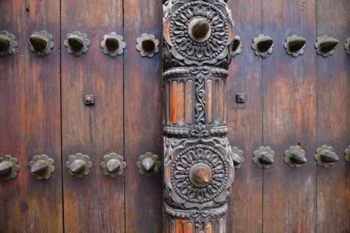 Close-up of intricately carved wooden door in Stone Town, Zanzibar, showcasing Swahili architecture on the walking tour.