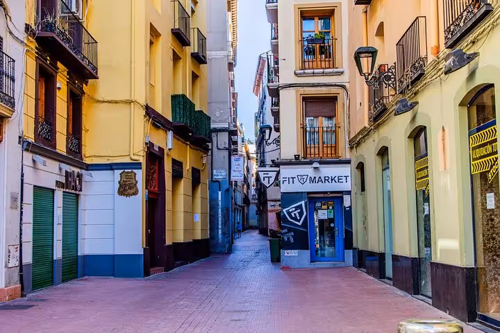 Narrow picturesque street in Zaragoza lined with colorful buildings and local shops, perfect for a guided city walk.