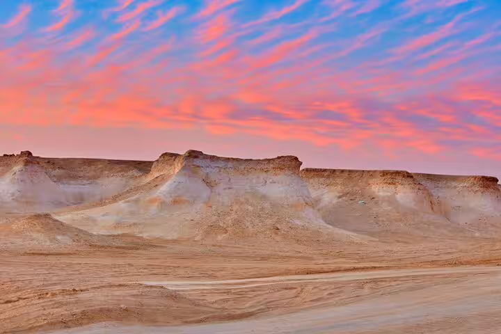 Zekreet desert's Mushroom Rock Formation at sunset with vibrant sky, a highlight of West Coast tours in Qatar.