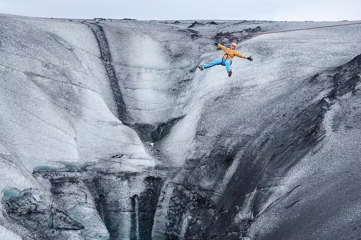 Adventurer zip-lining over dramatic glacial crevasse on an exciting Glacier Lagoon adventure tour in Iceland
