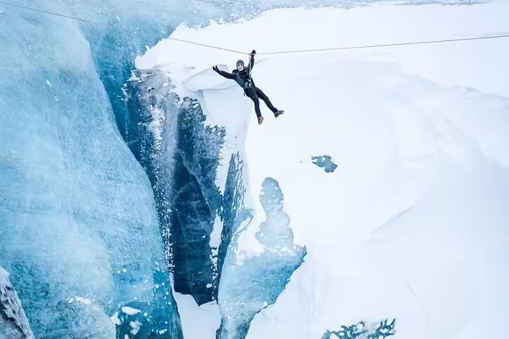 Daring adventurer ziplining over a stunning glacier crevasse near Iceland Glacier Lagoon on an epic ice adventure tour