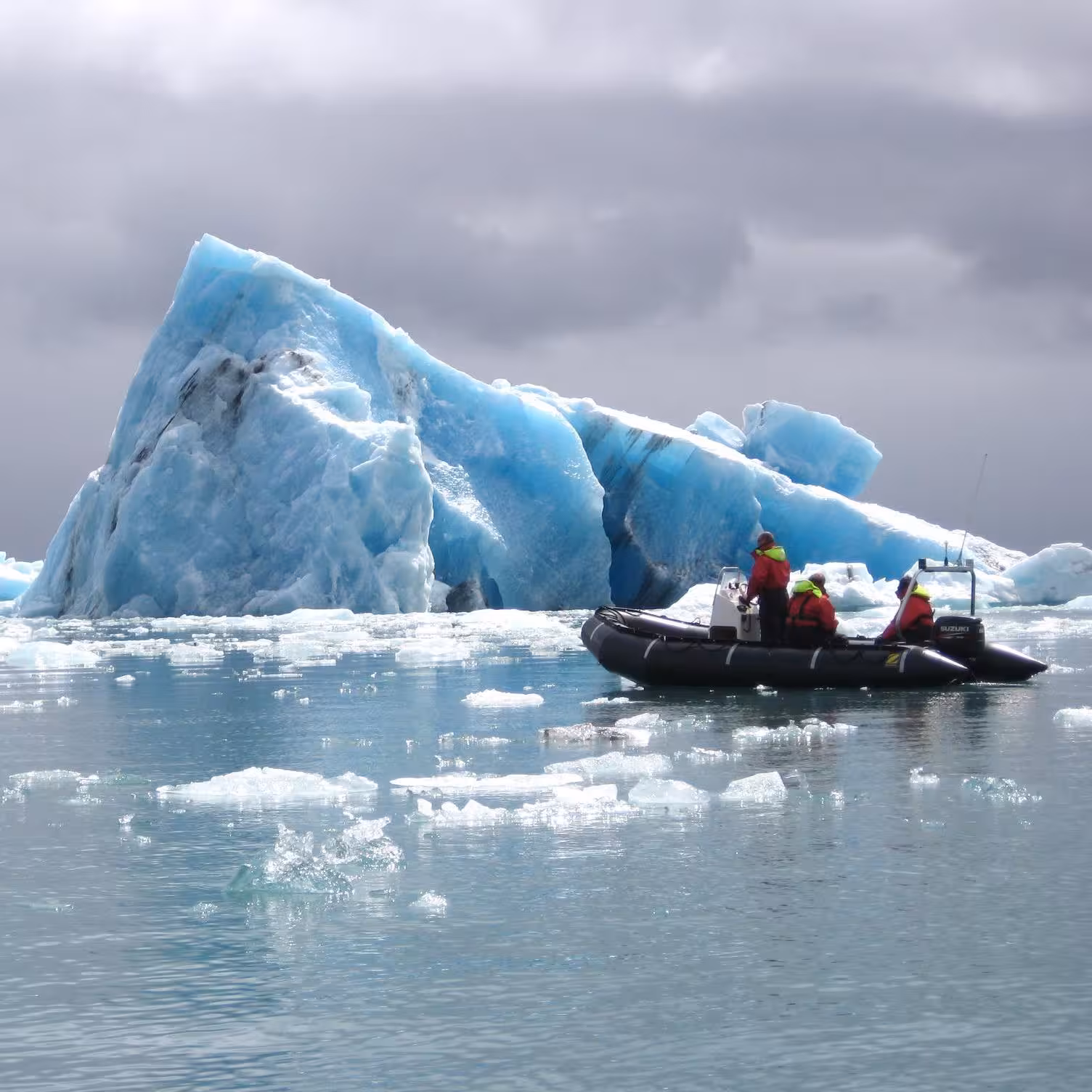 Zodiac boat tour navigating among stunning blue icebergs on Iceland glacier lagoon adventure