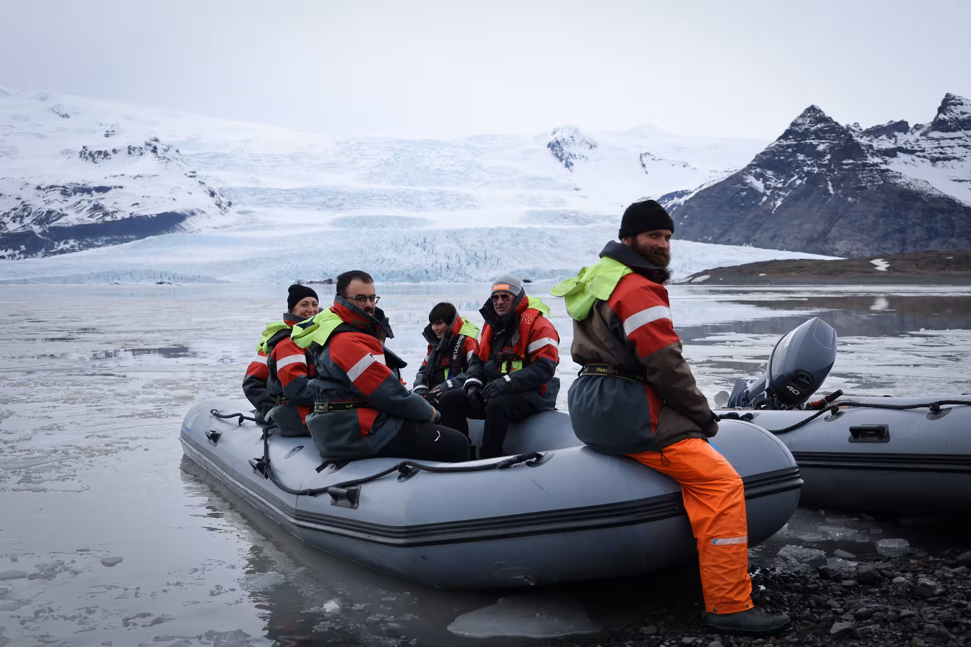 Tourists in red life jackets aboard a zodiac inflatable boat near Iceland glacier lagoon on a guided tour