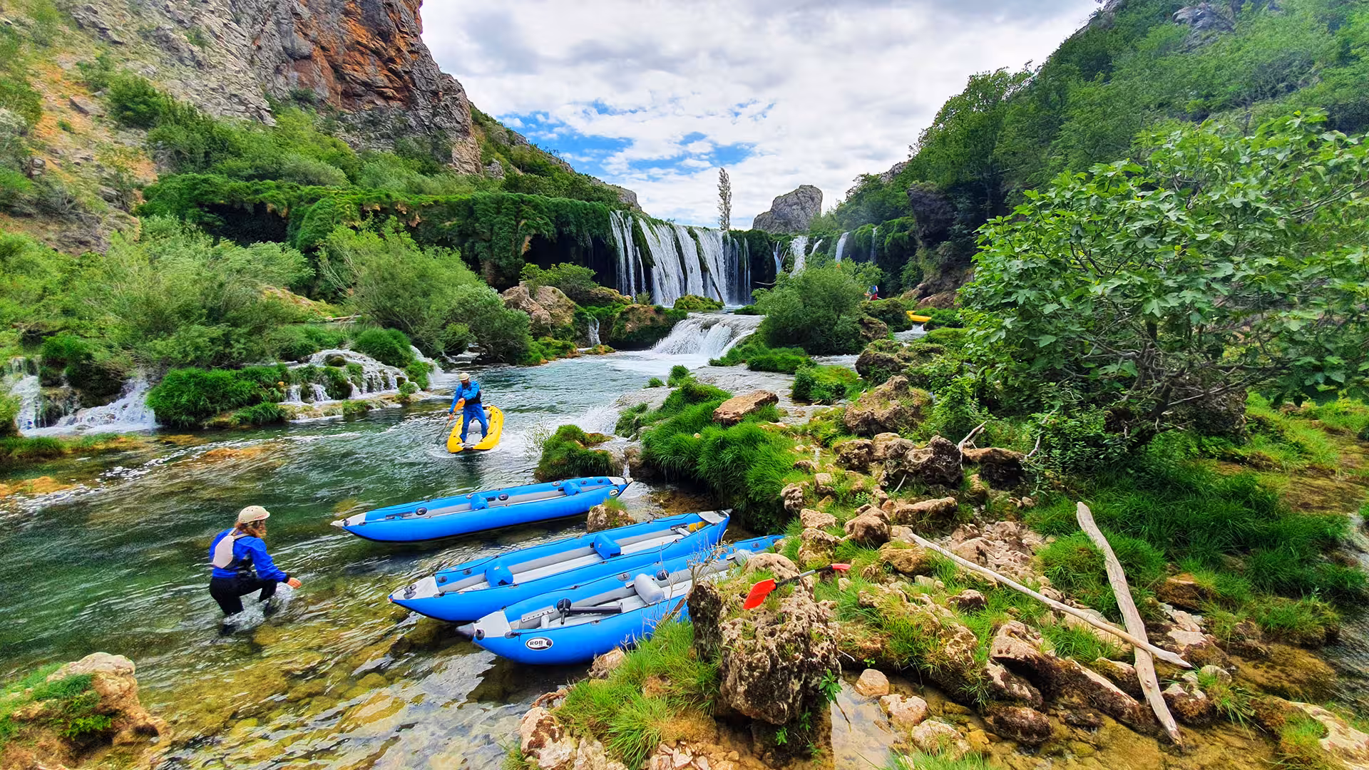Big waterfall at the Zrmanja river, lush green nature, a few kayaks "parked" near the coast