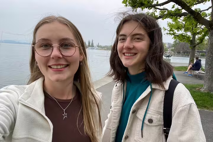 Two travelers smiling on Lake Zug waterfront during a Zug scavenger hunt and sights self-guided tour