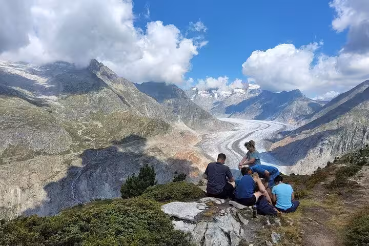 Travelers resting at viewpoint above the Aletsch Glacier, longest in the Alps, on a Zurich day trip