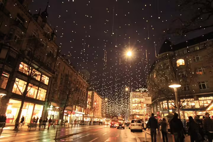 Festive night scene in Zurich with glowing street lights and bustling holiday shoppers.