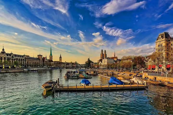 Panoramic view of Zurich old town waterfront with boats on Limmat River and historic church spires