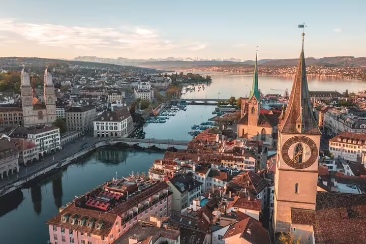 Aerial panoramic view of Zurich old town with river Limmat, clock tower spires, and Lake Zurich at sunset