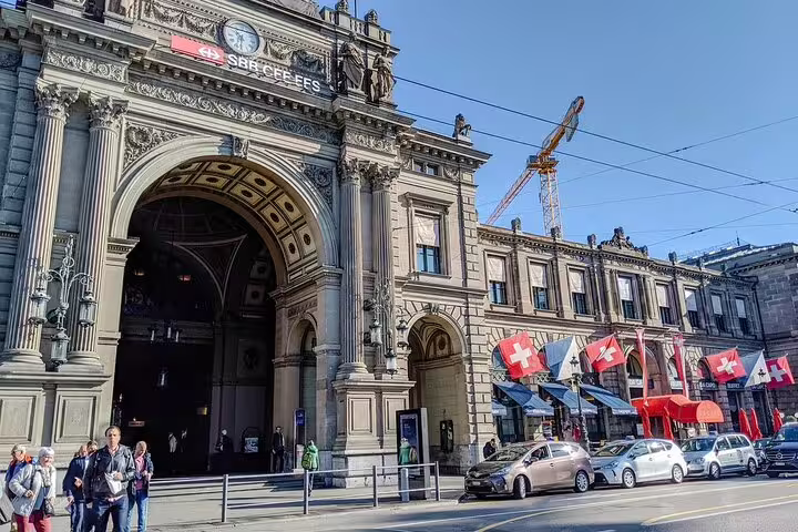 Zurich Main Station historic façade with Swiss flags and grand arched entrance on a sunny day