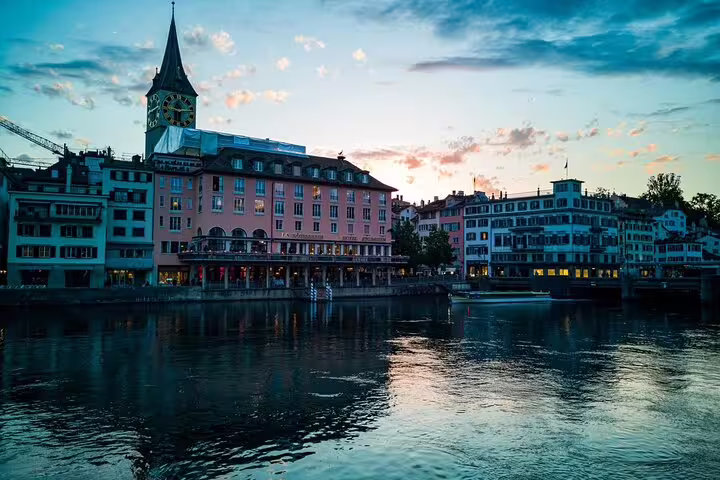 Zurich old town waterfront along the Limmat River at dusk with St. Peter's Church clock tower