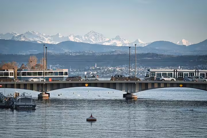 Zurich bridge over lake with snow-capped Alps and trams in panoramic city view