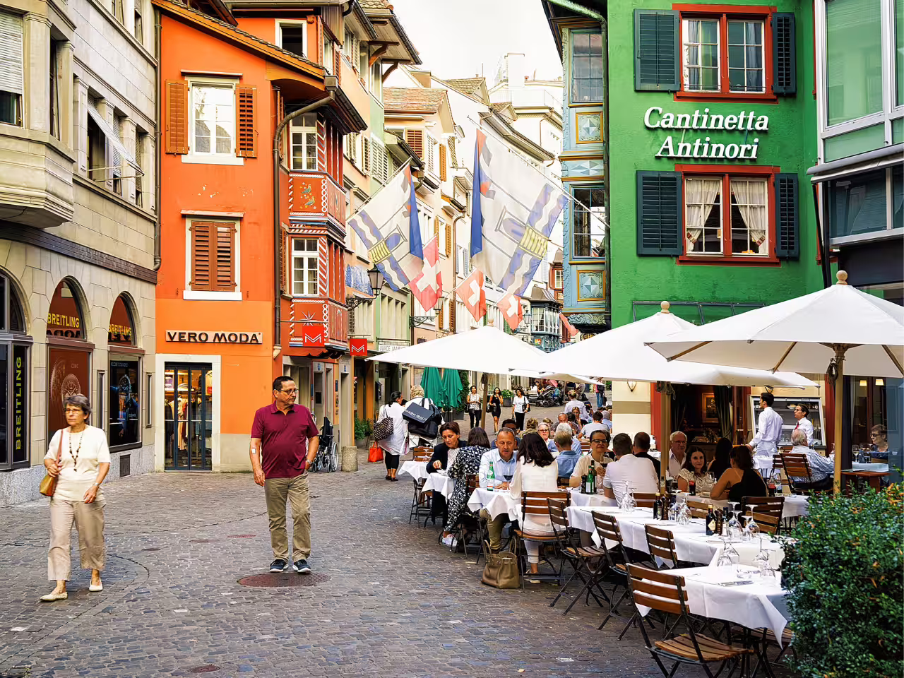 Lively Zurich street with colorful buildings and bustling outdoor cafes, perfect for experiencing Swiss culture.