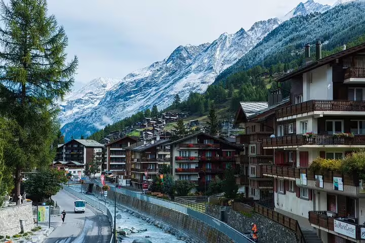 Alpine village of Zermatt with snow-capped mountains, chalet-style buildings, and a mountain stream in Switzerland