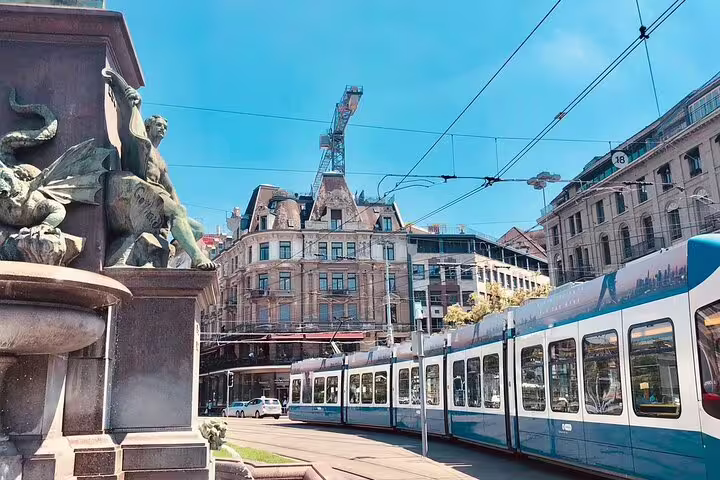Zurich tram passing bronze dragon fountain with historic European buildings and blue sky