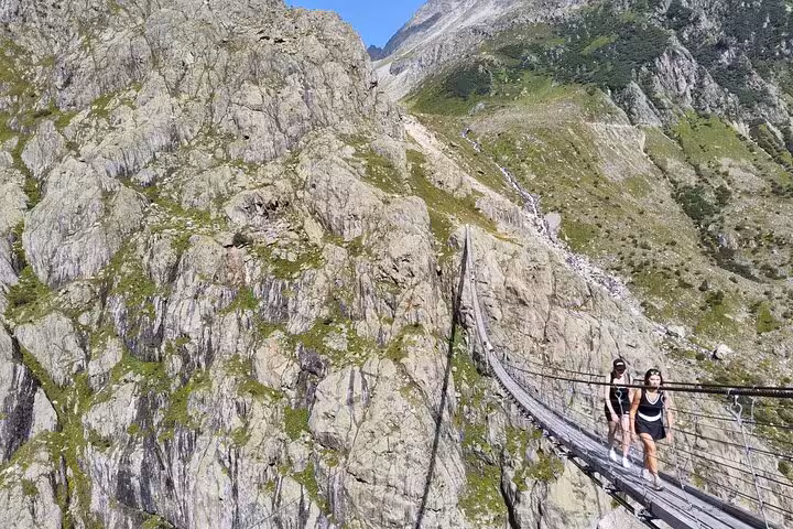 Hikers crossing Trift Suspension Bridge on a Zurich day trip adventure in the Swiss Alps near Gadmen