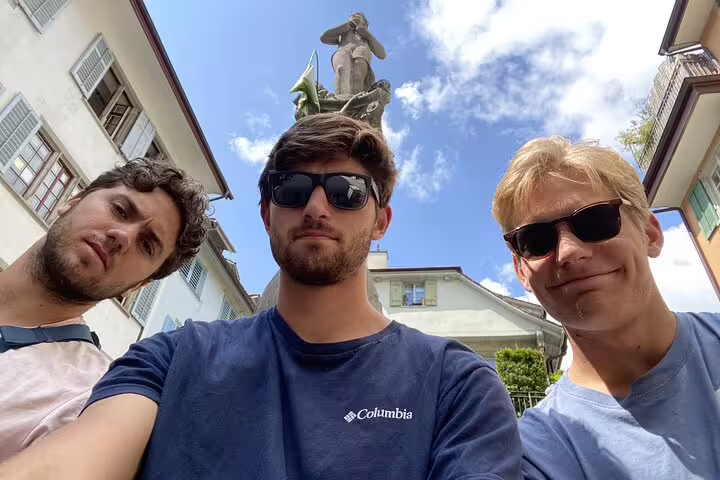 Three young men taking a selfie in front of a historic statue in Zurich city center